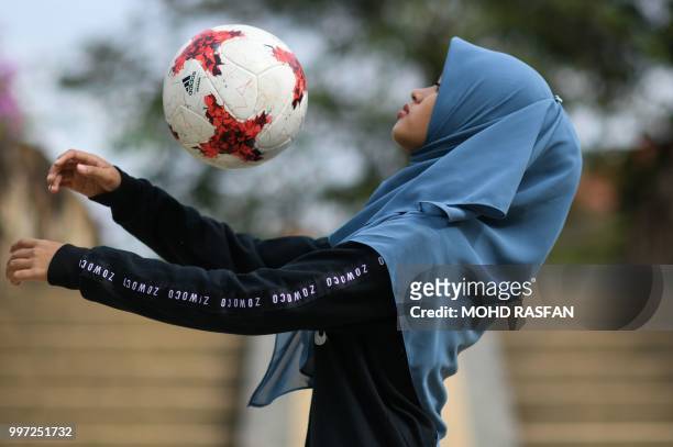 In this photograph taken on July 11 female football freestyler Qhouirunnisa' Endang Wahyudi performs a chest stall at a park in Klang, on the...