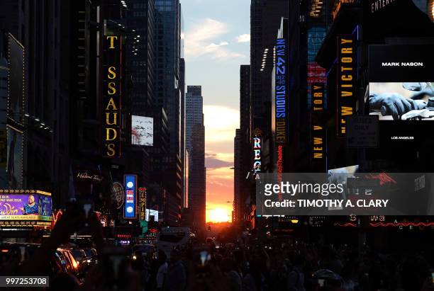 The sun sets as seen from 42nd street in Times Square in New York City on July 12, 2018 during Manhattanhenge. - Manhattanhenge, sometimes also...