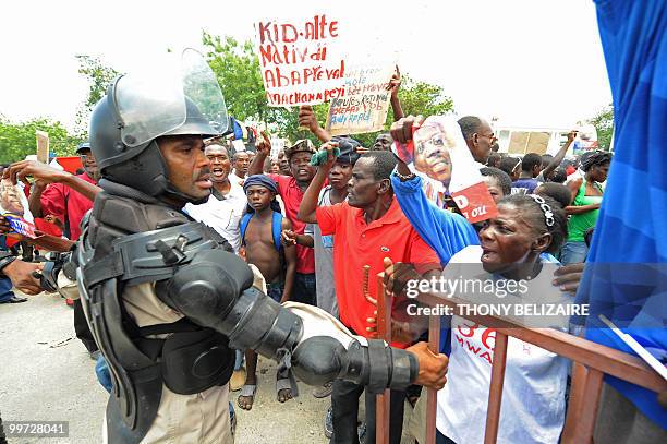 Haitians face riot police as they demonstrate near the presidential palace in Port-au-Prince on May 17, 2010 against President Rene Preval's decision...