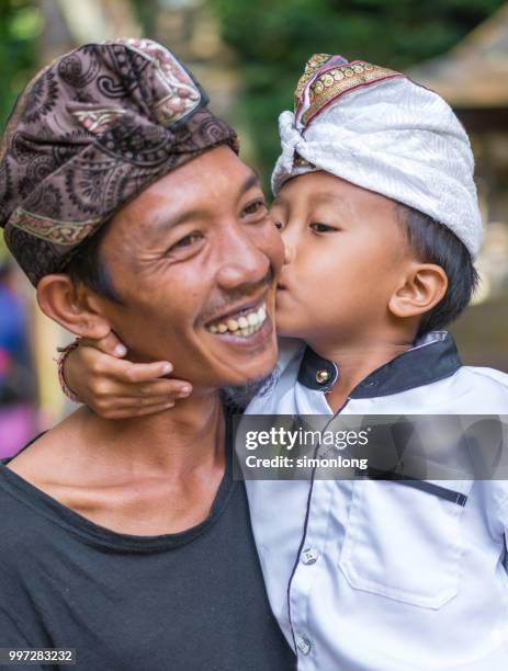 an indonesian boy kissing his father's cheek. bali, indonesia - denpasar stock pictures, royalty-free photos & images