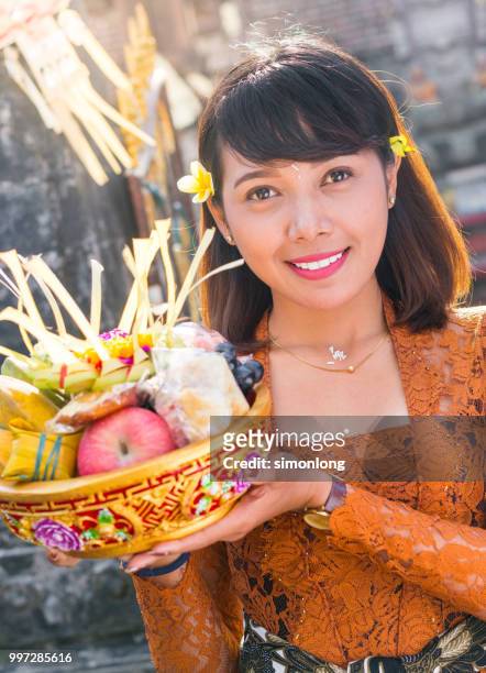 portrait of a balinese young woman with offerings - balinese culture stock-fotos und bilder