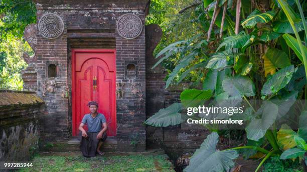 portrait of a young man sitting in front of a door - denpasar stock pictures, royalty-free photos & images