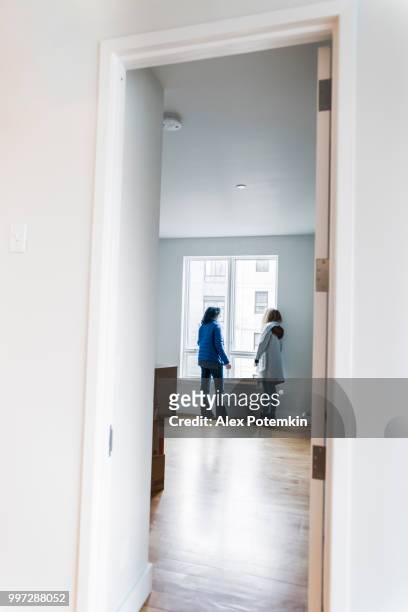 the mature attractive woman, the single mother, and her daughters looking around the new empty apartment. - alex potemkin or krakozawr stock pictures, royalty-free photos & images