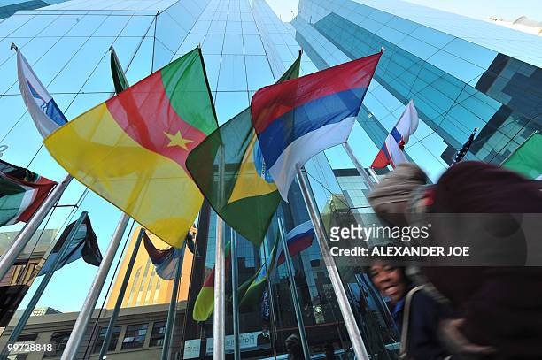 People walk pass a building as they go to work in Johannesburg on May 17, 2010 with the flags of the 32 countries competing in the Fifa World Cup...