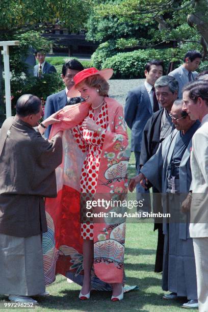 Princess Diana, Princess of Wales is presented a kimono while Prince Charles, Prince of Wales watches during a garden party at Nijo Castle on May 9,...