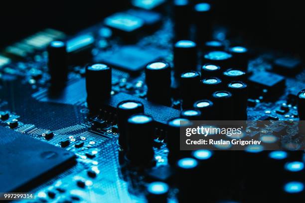 computer motherboard closeup blue color on dark background - resistor stock pictures, royalty-free photos & images