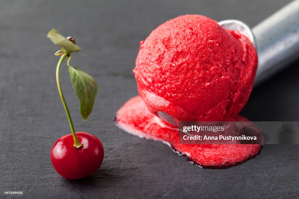 Ice cream, fresh cherry, raspberry, strawberry, cranberry, red sorbet, scoop. Black stone background