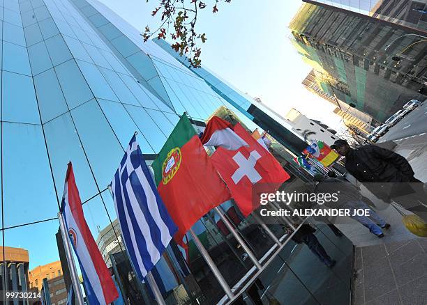 People walk pass a building as they go to work in Johannesburg on May 17, 2010 with the flags of the 32 countries competing in the Fifa World Cup...