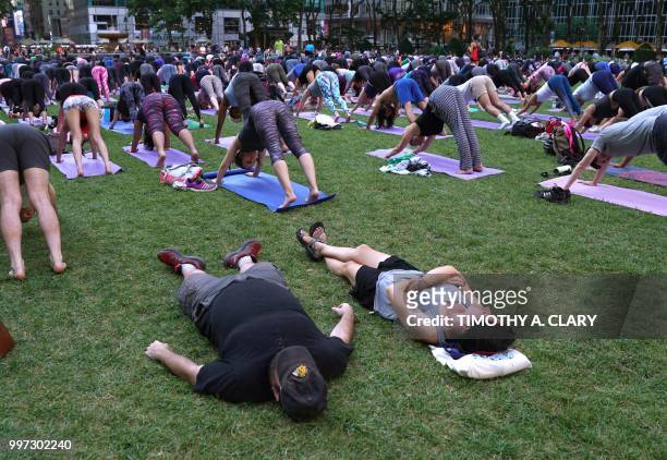 Couple of tourists nap in the grass as people participate in an outdoor yoga event in Bryant Park in New York City July 12, 2018.