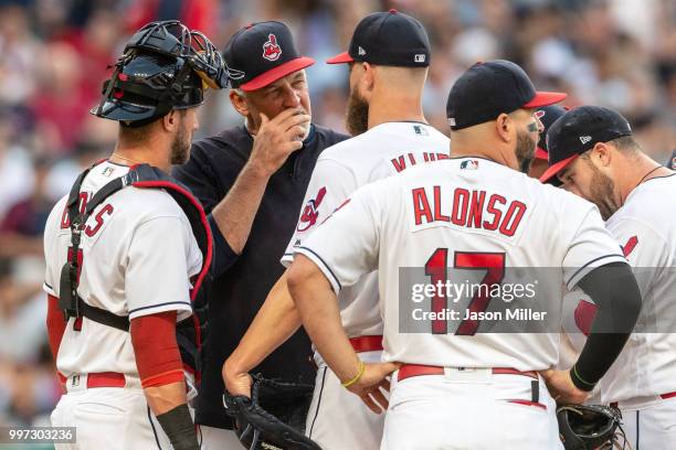 Pitching coach Carl Willis of the Cleveland Indians comes to the mound to talk with starting pitcher Corey Kluber and catcher Yan Gomes during the...