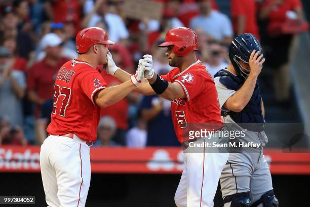 Mike Trout congratulates Albert Pujols of the Los Angeles Angels of Anaheim after his two-run homerun while David Freitas of the Seattle Mariners...