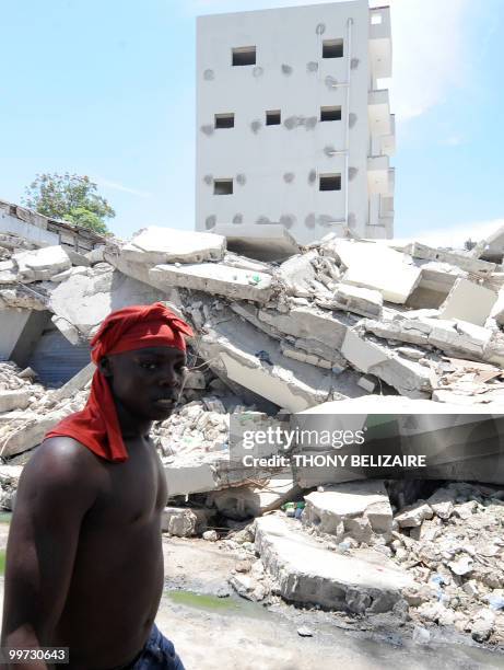 Haitian demonstrator walks past destroyed buildings during a protest near the presidential palace in Port-au-Prince on May 17, 2010 against President...