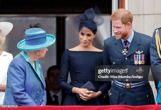 Queen Elizabeth II, Meghan, Duchess of Sussex and Prince Harry, Duke of Sussex, watch a flypast to mark the centenary of the Royal Air Force from the...
