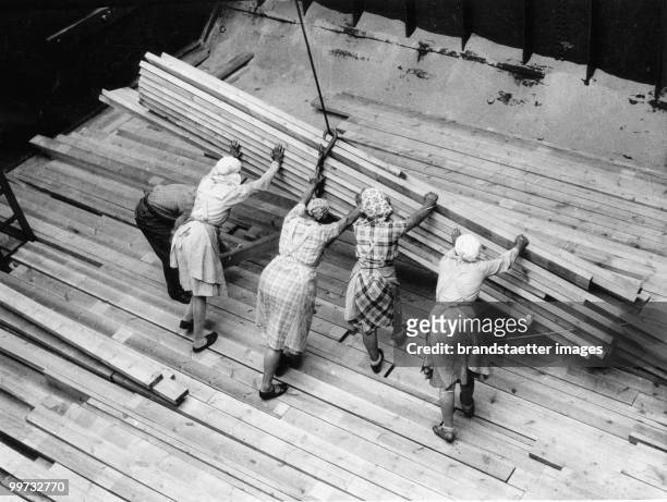 Due to the lack of men, women are working in the Finnish ports along the Baltic sea, usually with a man acting as foreman. The woman are seen heaving...