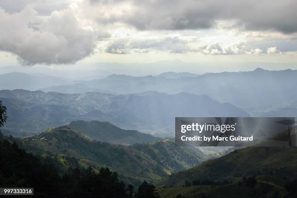 sunlight illuminating a valley as it peaks through the clouds as seen from cerro el pital, el salvador - colina fotografías e imágenes de stock