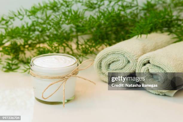 jar with cream, towels and greens on bathroom countertop - loofah stock-fotos und bilder