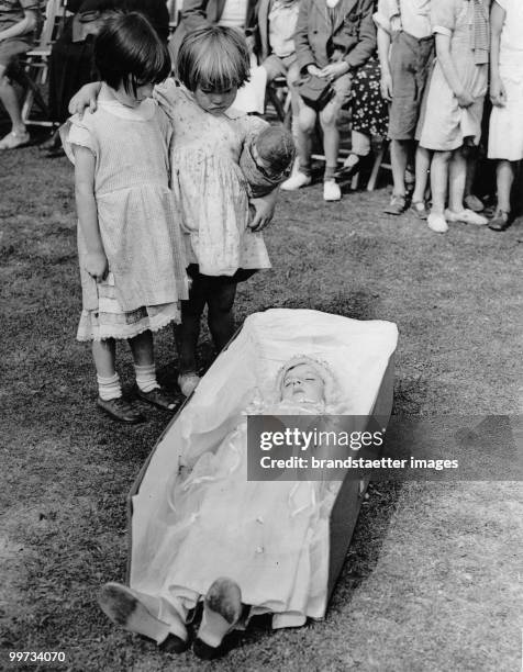 Two children at a children´s fancy dress parade looking at a girl dressed up as a doll. England. Photographie. August 23th 1937.