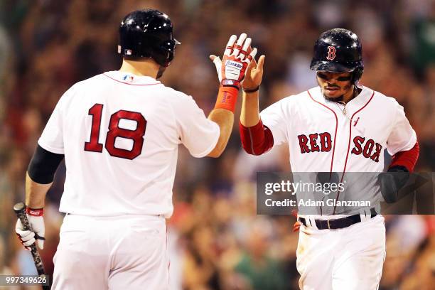 Mookie Betts high fives Mitch Moreland of the Boston Red Sox as he returns to the dugout after scoring in the seventh inning of a game against the...