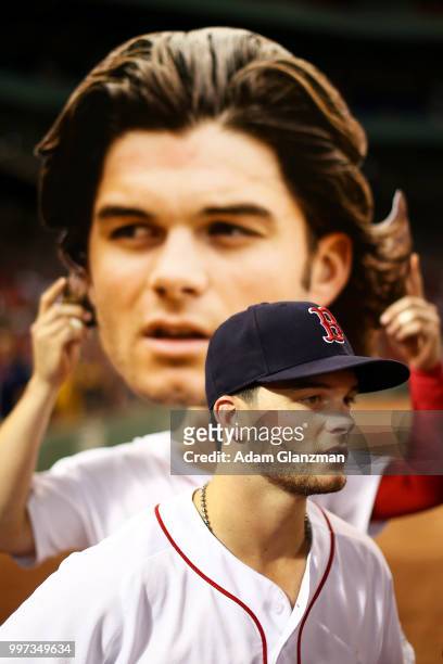 Brock Holt of the Boston Red Sox holds up a cut out of the face of Andrew Benintendi of the Boston Red Sox as he is interviewed by NESN reporter...