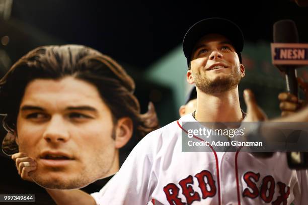 Brock Holt of the Boston Red Sox holds up a cut out of the face of Andrew Benintendi of the Boston Red Sox as he is interviewed by NESN reporter...