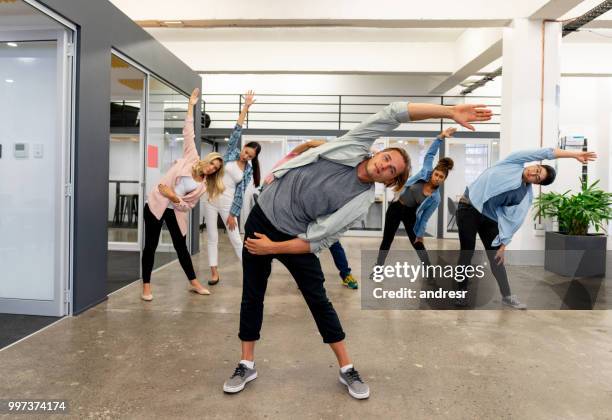 group of workers on an active break at a creative office - office yoga stock pictures, royalty-free photos & images