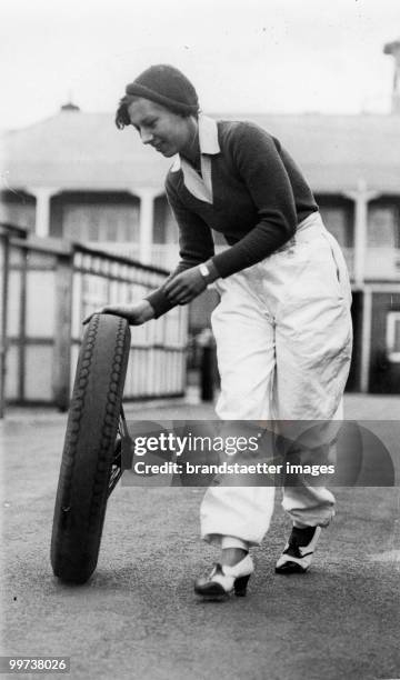 Female Racer rolling a Spare Wheel. The picture shows a female racer rolling a spare wheel to the paddock at an race for women held on the famous...