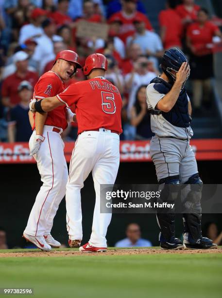 Mike Trout congratulates Albert Pujols of the Los Angeles Angels of Anaheim after his two-run homerun while David Freitas of the Seattle Mariners...