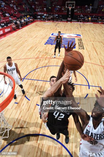 Alpha Kaba of the Atlanta Hawks and Caleb Swanigan of the Portland Trail Blazers reach for the ball during the 2018 Las Vegas Summer League on July...