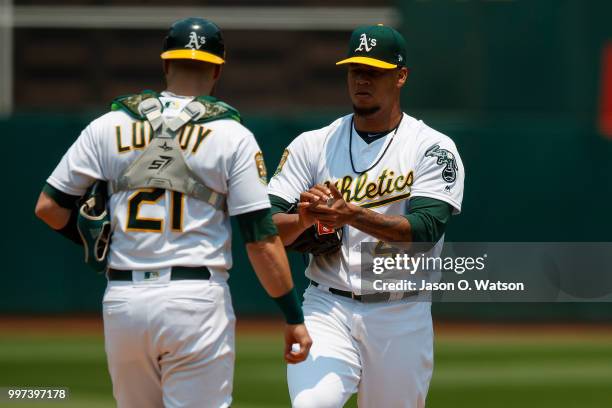 Jonathan Lucroy of the Oakland Athletics talks to Frankie Montas during a mound visit during the first inning against the Cleveland Indians at the...