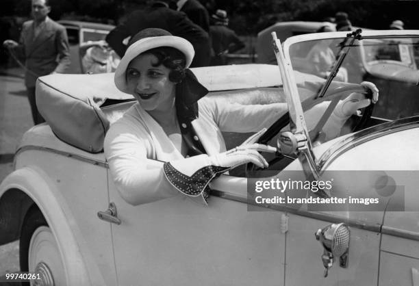 Elegant lady posing in a car. She wears gloves which are especially designed for female drivers. Photograph. Around 1930. (Photo by Austrian Archives