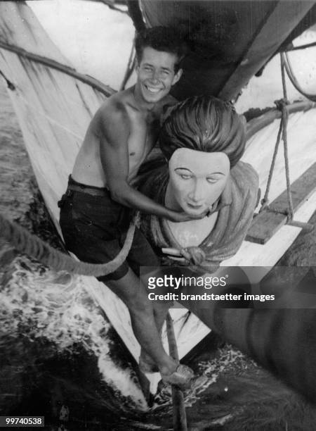 Member of the crew of the Finnish barque 'Herzogin Cecile' is posing with the figurehead known to the crew as 'The Duchess'. Photograph. 1936. (Photo...