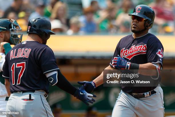 Edwin Encarnacion of the Cleveland Indians is congratulated by Yonder Alonso after hitting a home run against the Oakland Athletics during the...