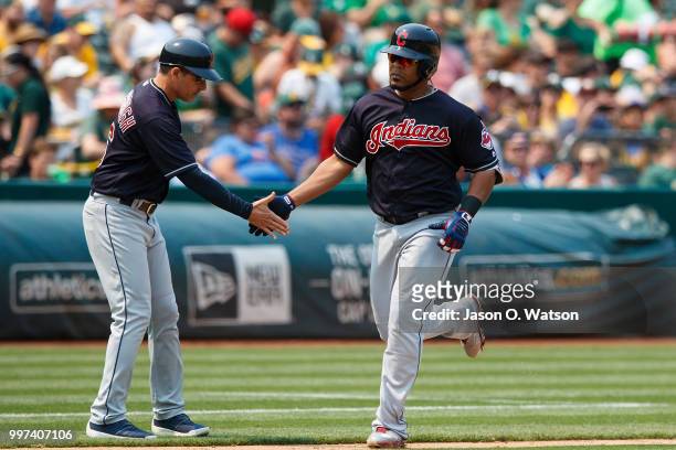Edwin Encarnacion of the Cleveland Indians is congratulated by third base coach Mike Sarbaugh after hitting a home run against the Oakland Athletics...