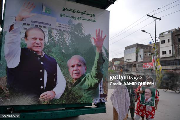 Supporters of Pakistan's ousted prime minister Nawaz Sharif hold posters of him as they gather at the venue where his younger brother Shahbaz Srarif...