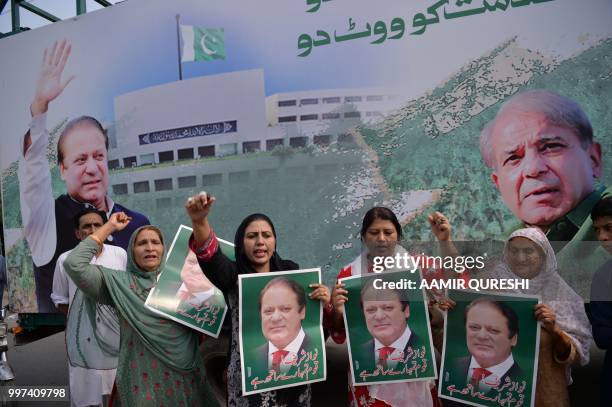 Supporters of Pakistan's ousted prime minister Nawaz Sharif hold posters of him and chant slogans as they gather at the venue where his younger...