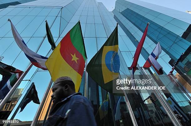 Man walks pass a building as he goes to work in Johannesburg on May 17, 2010 with the flags of the 32 countries competing in the Fifa World Cup that...