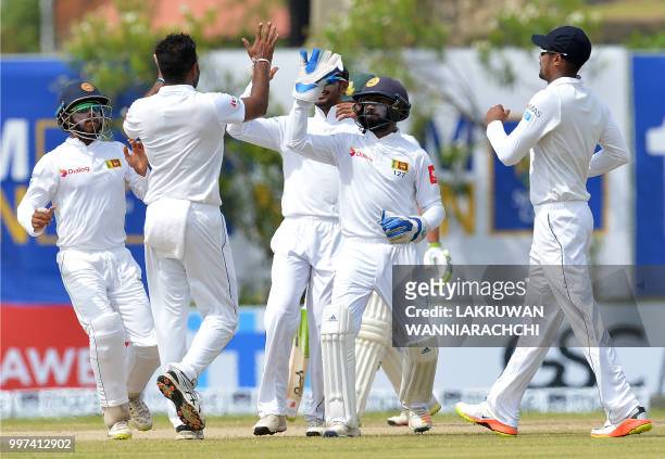 Sri Lankan cricketer Dilruwan Perera celebrates with his teammates after he dismissed South Africa's Dean Elgar during the second day of the opening...
