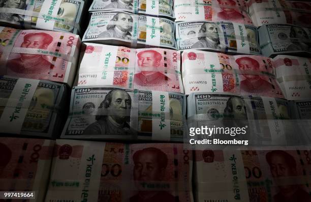 Genuine bundles of Chinese one-hundred yuan banknotes and U.S. One-hundred dollar banknotes are arranged for a photograph at the Counterfeit Notes...
