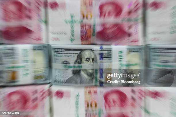 Genuine bundles of Chinese one-hundred yuan banknotes and U.S. One-hundred dollar banknotes are arranged for a photograph at the Counterfeit Notes...