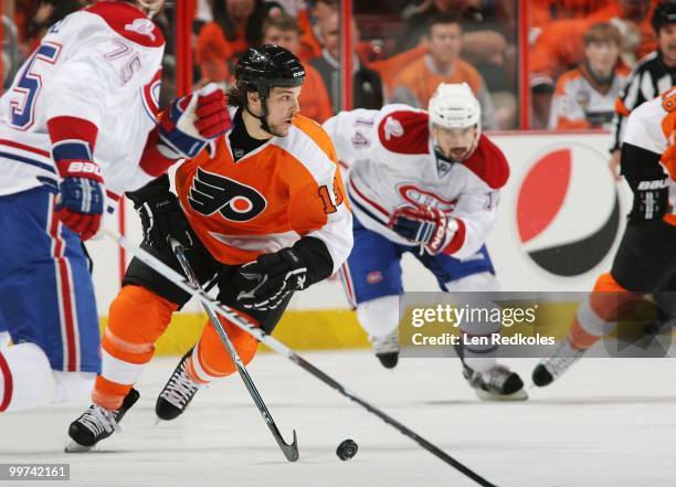 Dan Carcillo of the Philadelphia Flyers skates the puck between Hall Gill and Tomas Plekanec of the Montreal Canadiens in Game One of the Eastern...