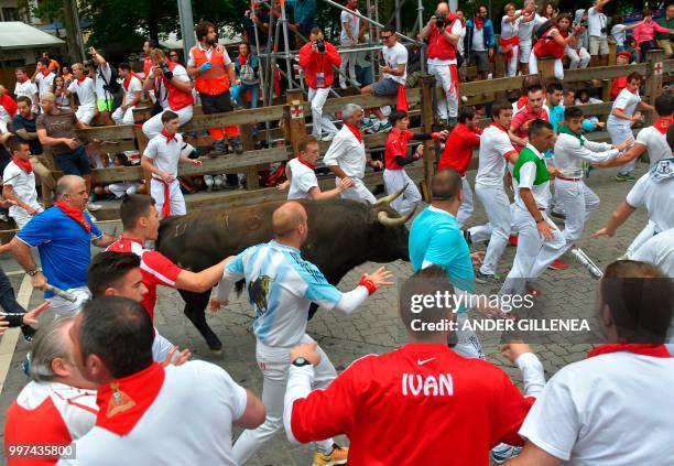 Participants run next to a Jandilla fighting bull during the seventh bullrun of the San Fermin festival in Pamplona, northern Spain on July 13, 2018....