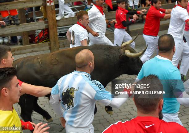 Participants run next to Jandilla fighting bull during the seventh bullrun of the San Fermin festival in Pamplona, northern Spain on July 13, 2018. -...