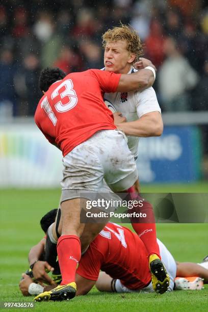 Billy Twelvetrees of England Saxons is tackled by Suka Hufanga and Mateo Malupo of Tonga during the Churchill Cup match between England Saxons and...