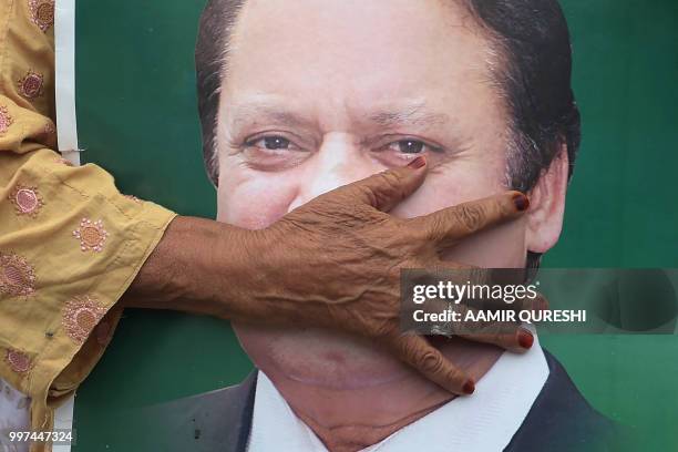 Supporter of ousted former Pakistani prime minister Nawaz Sharif holds his picture at the venue where his younger brother Shahbaz Srarif will lead a...