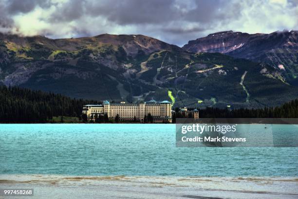 a mountain backdrop to the fairmont chateau lake louise - chateau lake louise stockfoto's en -beelden