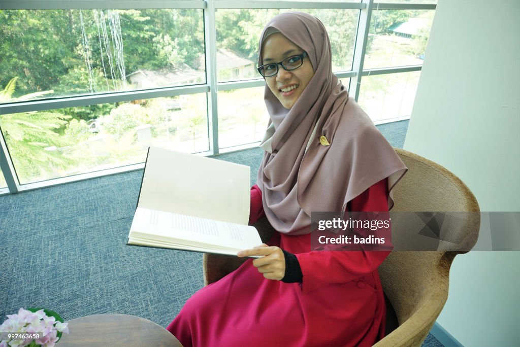 Beautiful young Muslimah students from Southeast Asian with hijab study in the library.