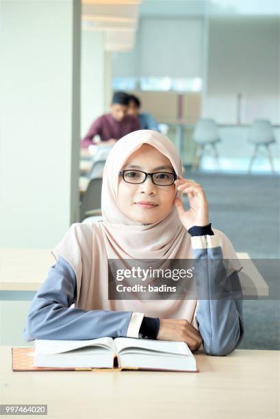 Beautiful young Muslimah students from Southeast Asian with hijab study in the library.