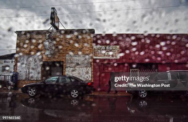 Man walks past boarded businesses on a rainy evening in North Omaha on Tuesday, May 1 in Omaha, NE. Over the past decade, concentrated efforts by...