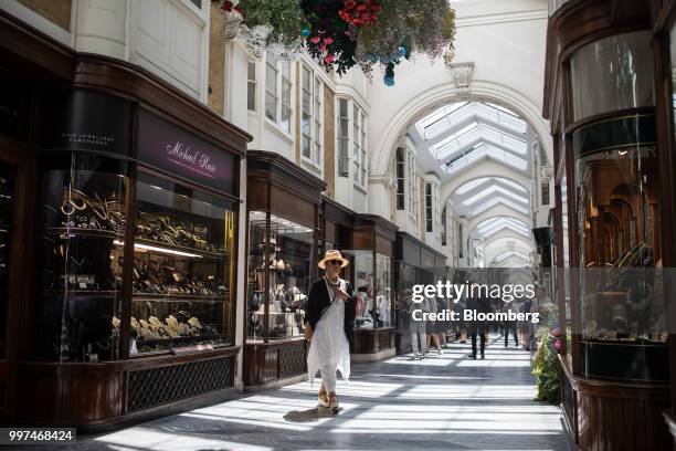 Shoppers browse the window displays of luxury goods stores as they walk through Burlington Arcade in central London, U.K., on Friday, Jun. 29, 2018....