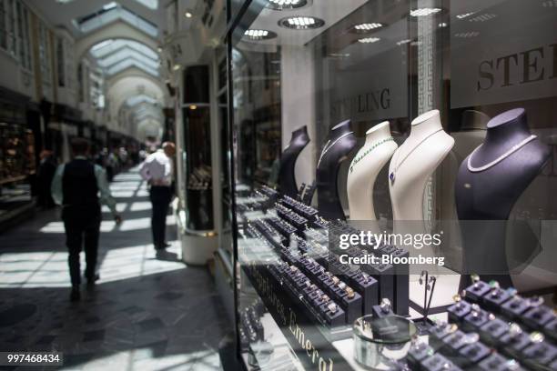 Jewelry sits on display as shoppers walk past luxury goods stores at the Burlington Arcade in central London, U.K., on Friday, Jun. 29, 2018....